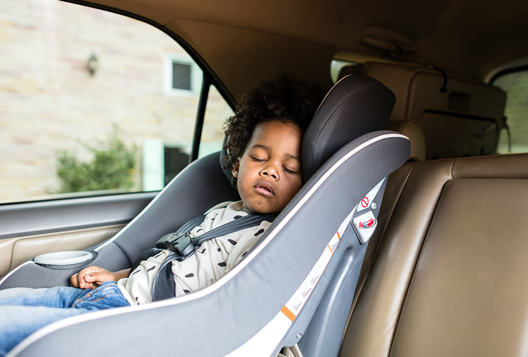 A small child asleep in a child car seat.