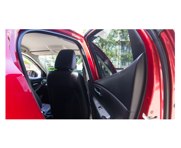 The open rear door of a car. The viewer looks into the car and can see the back of the passenger seat.