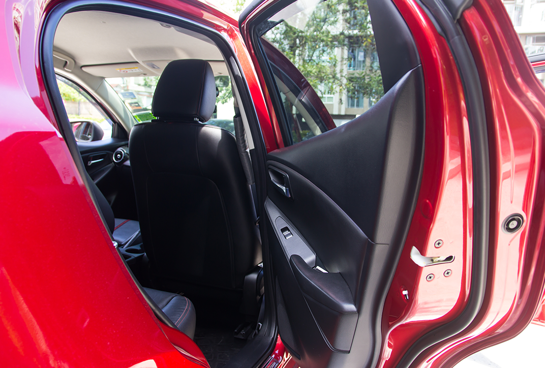 The open rear door of a car. The viewer looks into the car and can see the back of the passenger seat.