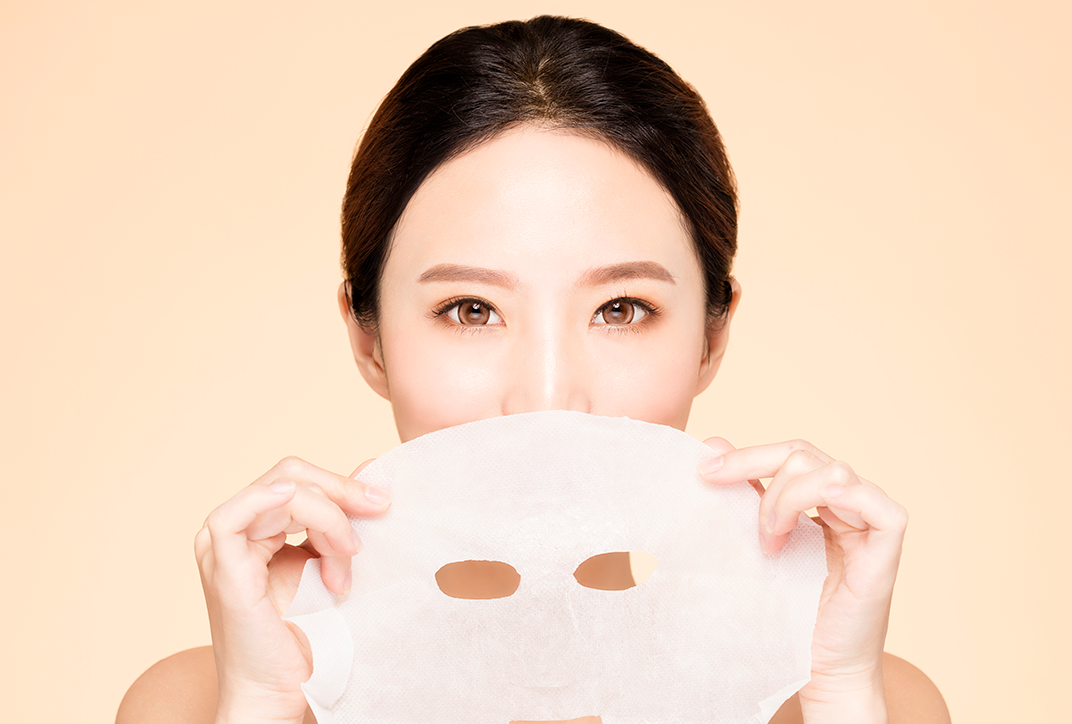 A lady using a fabric-based facial mask. A lady using a fabric-based facial mask.