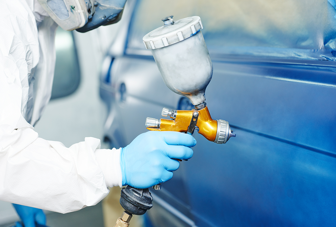 Man sieht die Hand einer Person, die ein Auto lackiert. Man sieht die Hand einer Person, die ein Auto lackiert.