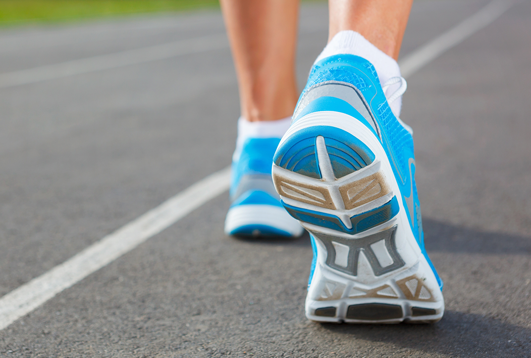 Die Füße einer Person, die gerade läuft. Sie trägt Sportschuhe.